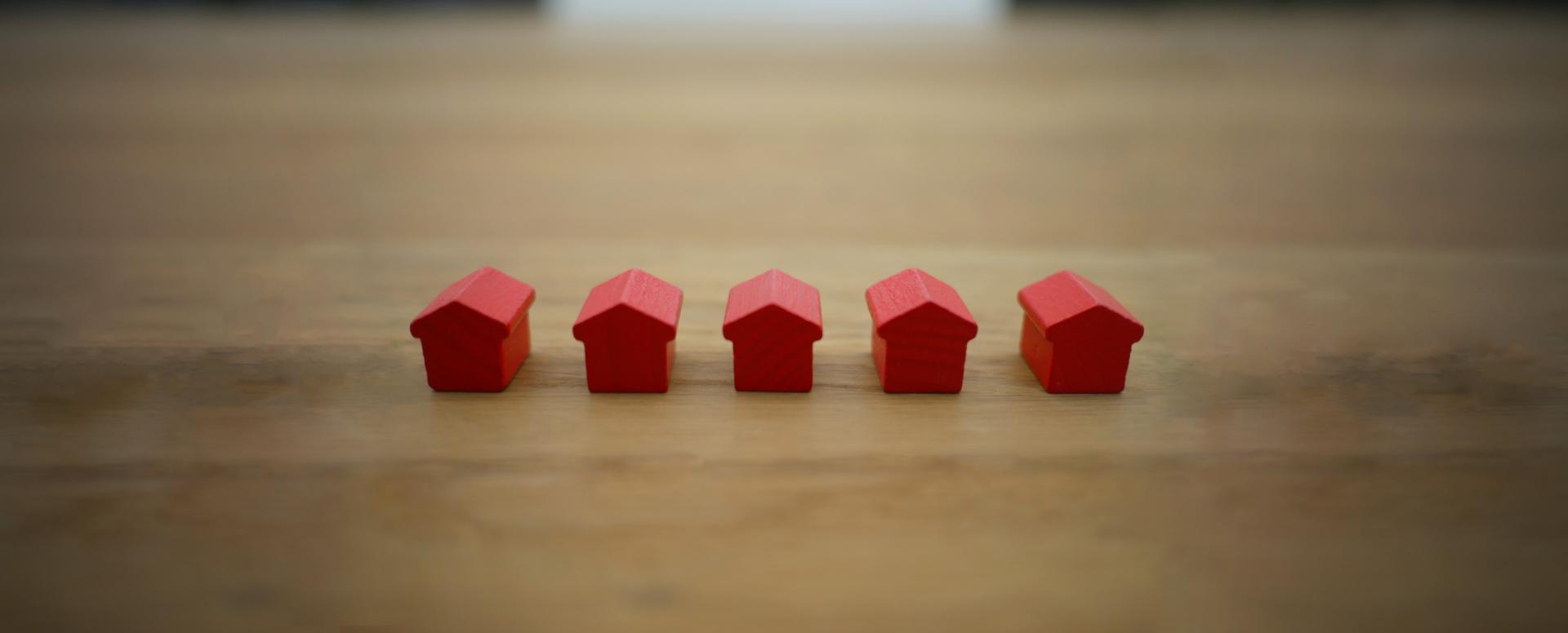 Five tiny red wooden house blocks on a wooden table